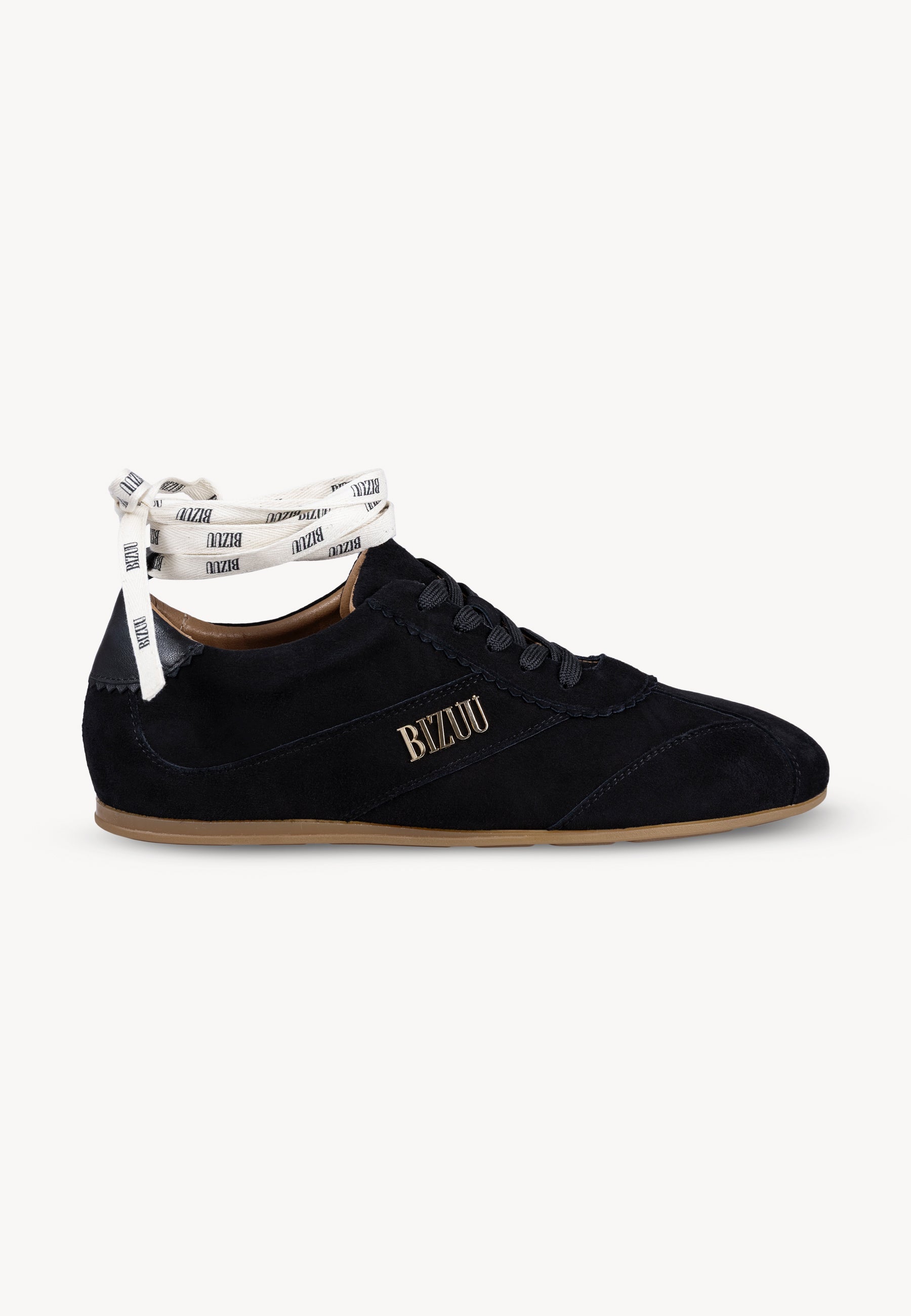 Czarne sneakersy LEOLA stojące bokiem, złote logo Bizuu na boku. But pokazany z dodatkową wstążką z logo Bizuu, którą można przewiązać na kostce.