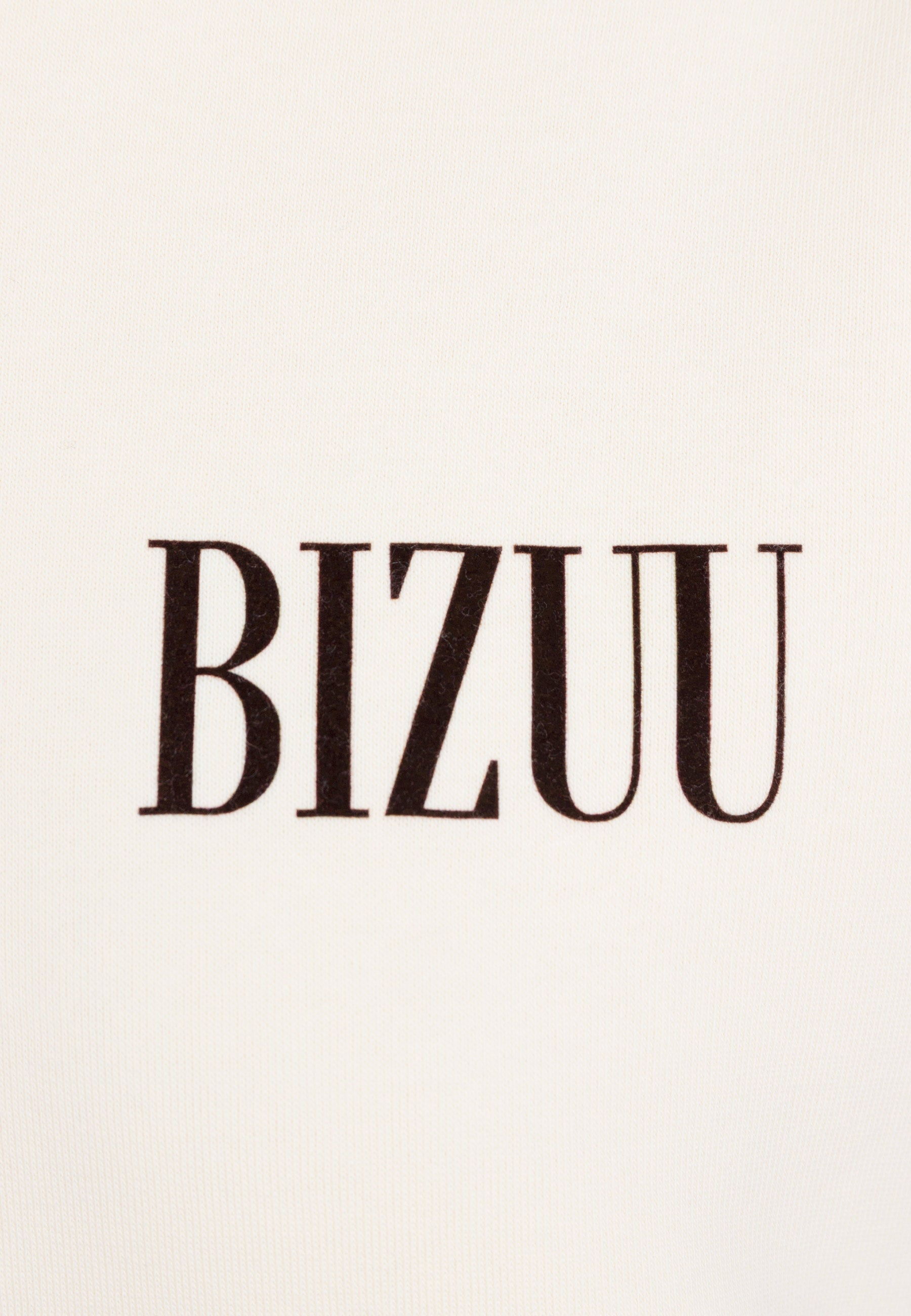 Zbliżenie na logo BIZUU na przodzie kremowej bluzy LINDI.