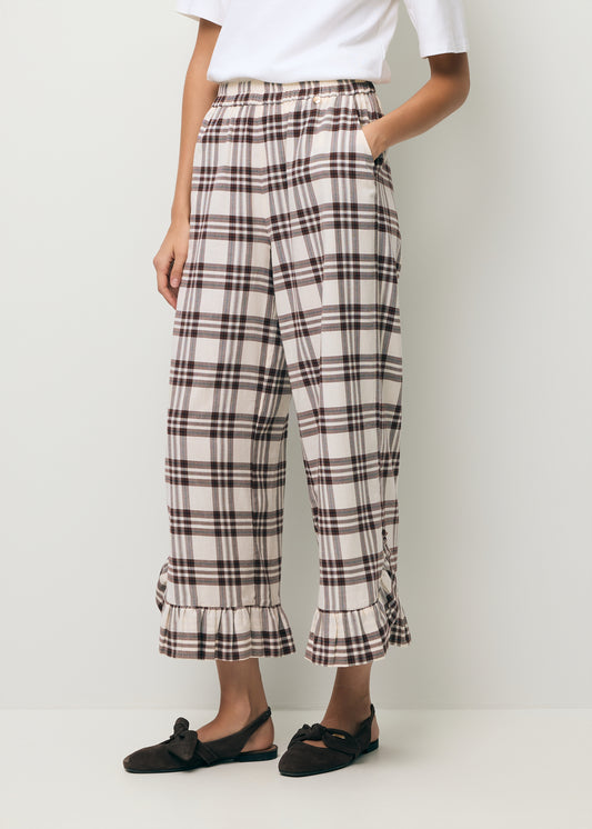 Zbliżenie na nogi modelki ubrane w spodnie w kratkę z ozdobną falbaną MELLA.