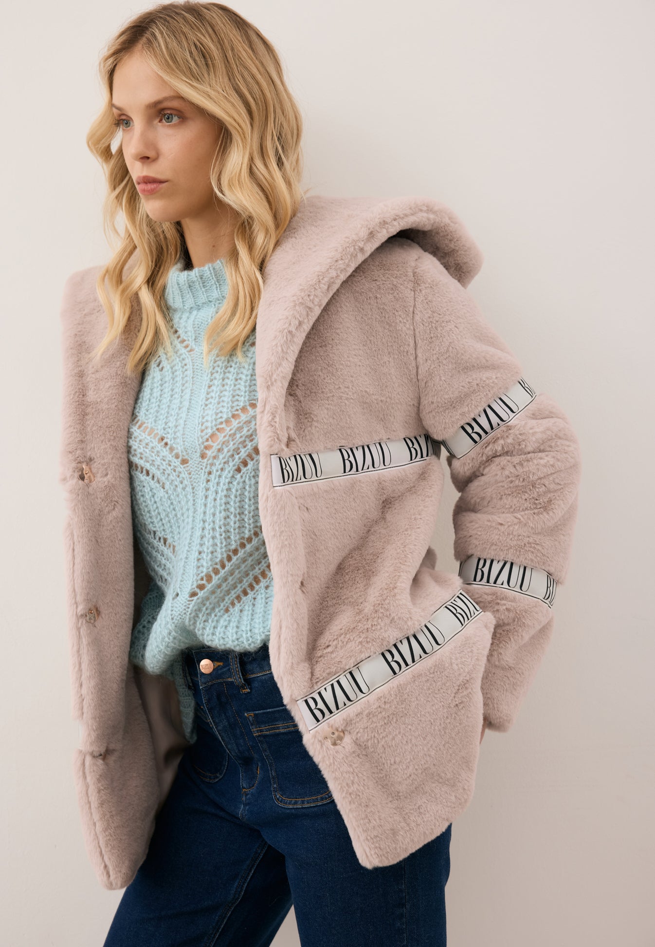 Zbliżenie na modelkę w rozpiętym futerku z kapturem MILANO, błękitnym swetrze ROSSO oraz spodniach DELPHI.