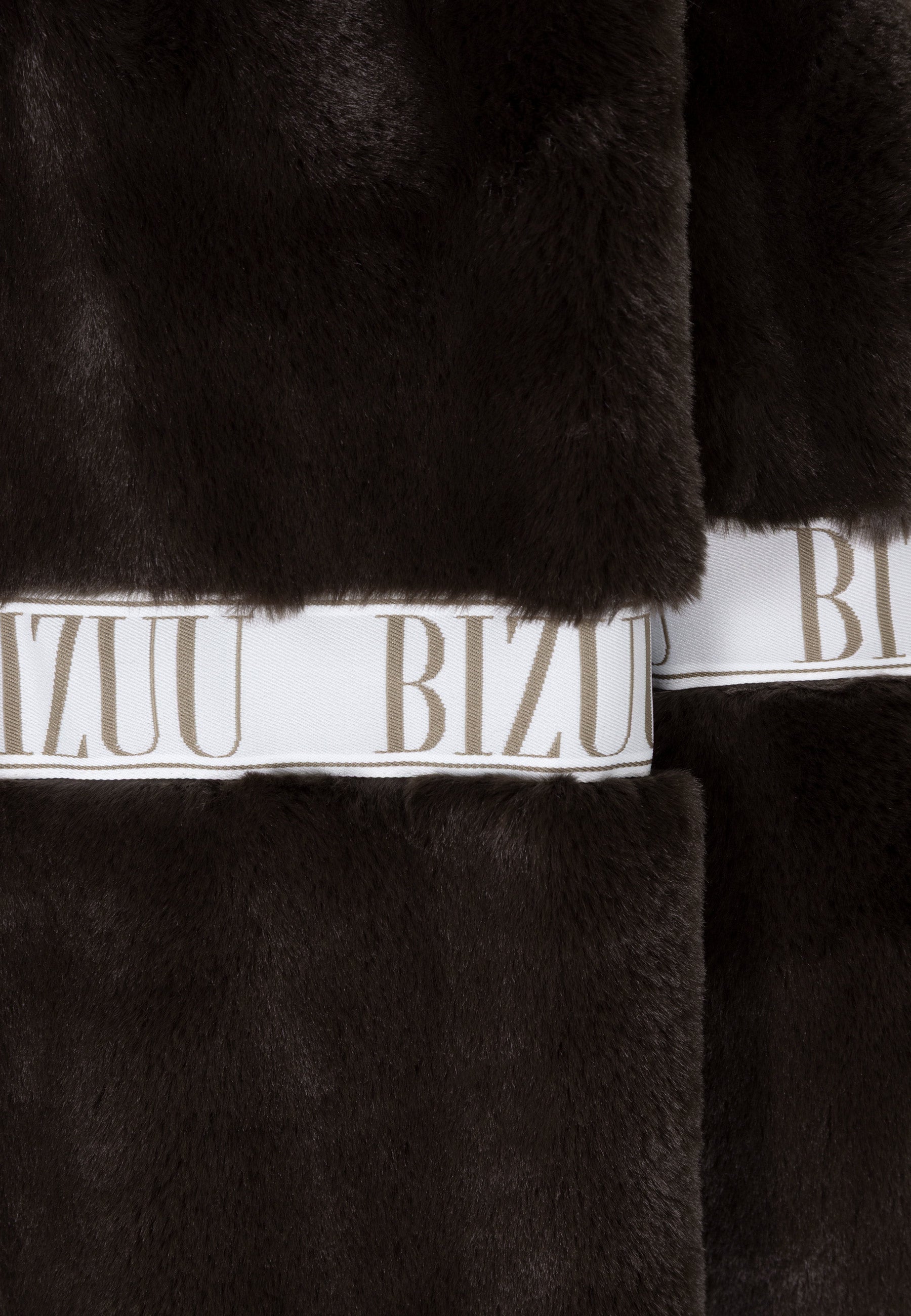 Zbliżenie na logowaną taśmę ozdabiającą brązowe futro MILANO.