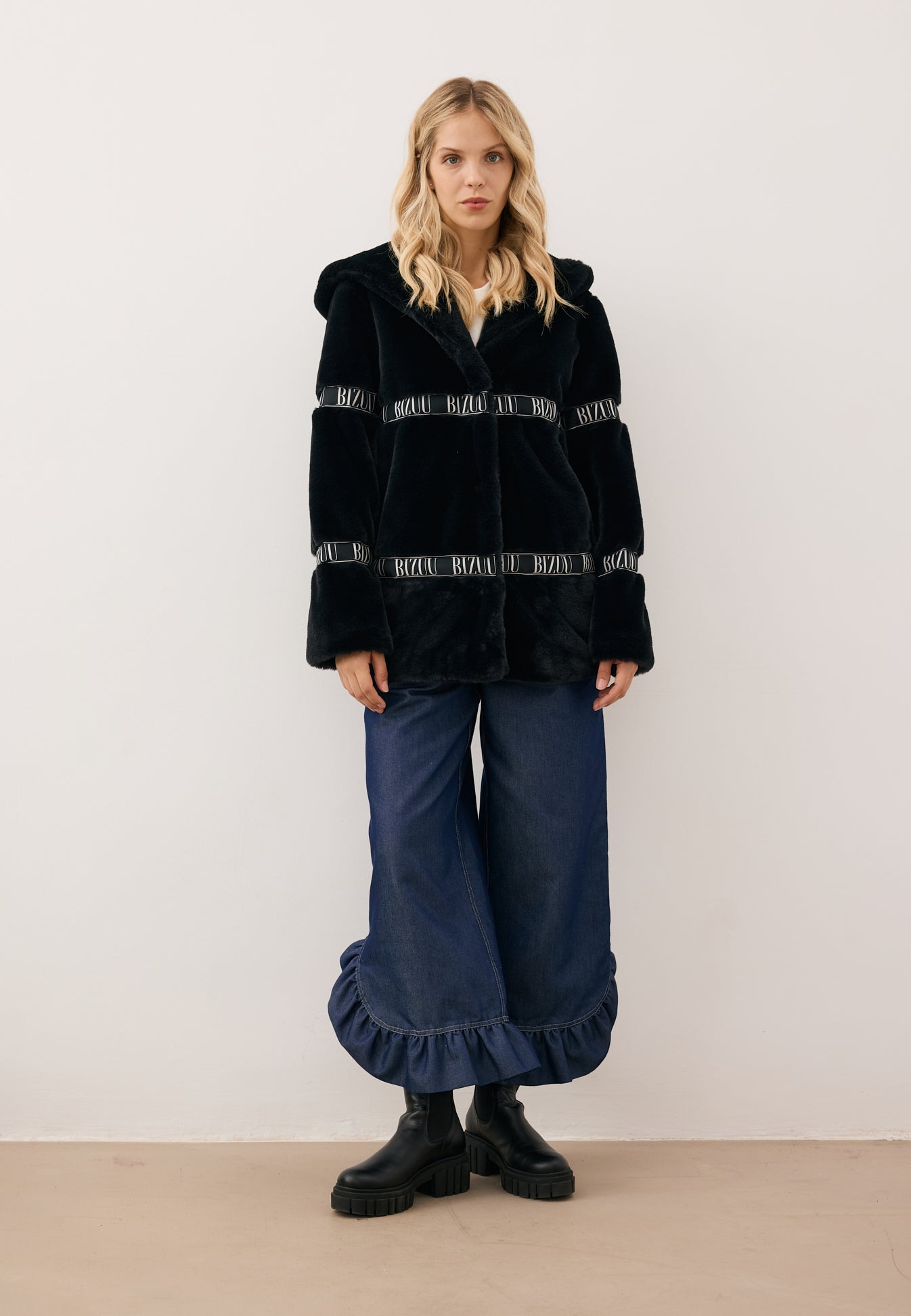 Modelka w czarnym futrze z kapturem i logo MILANO oraz jeansowe spodnie NELLA.