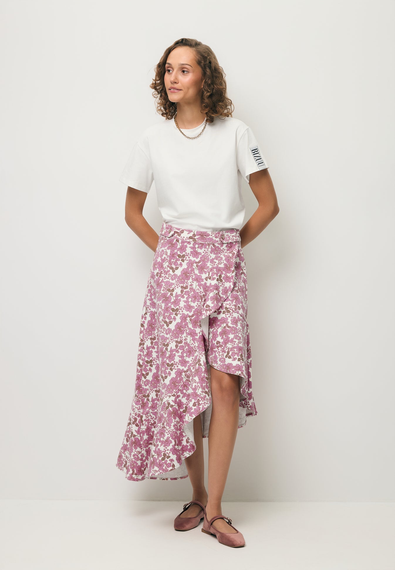 Modelka ubrana w printowaną asymetryczną spódnicę NIIAM oraz basicowy T-shirt TISHAM.