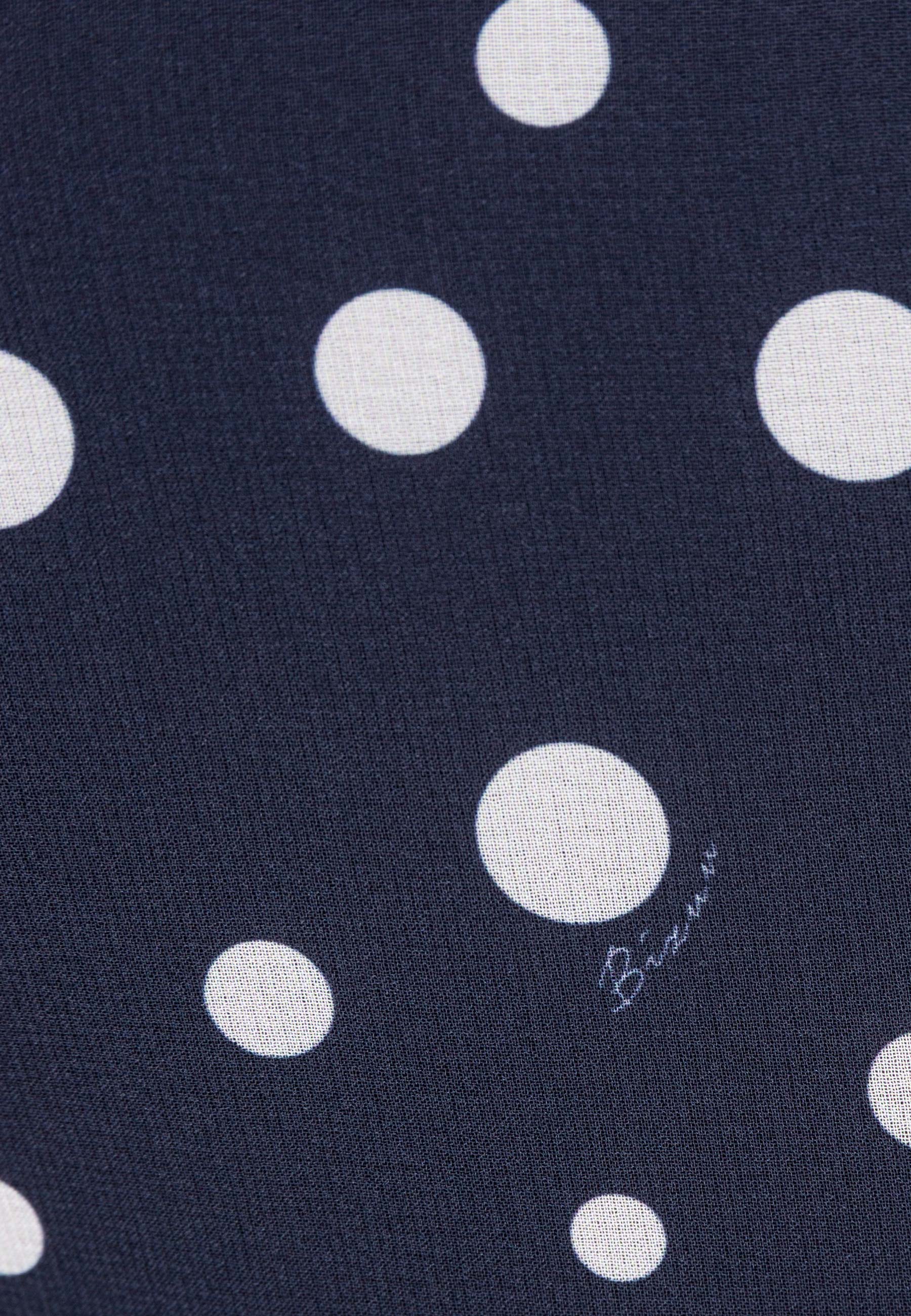 Zbliżenie na print w groszki z logo na sukience NYLA.