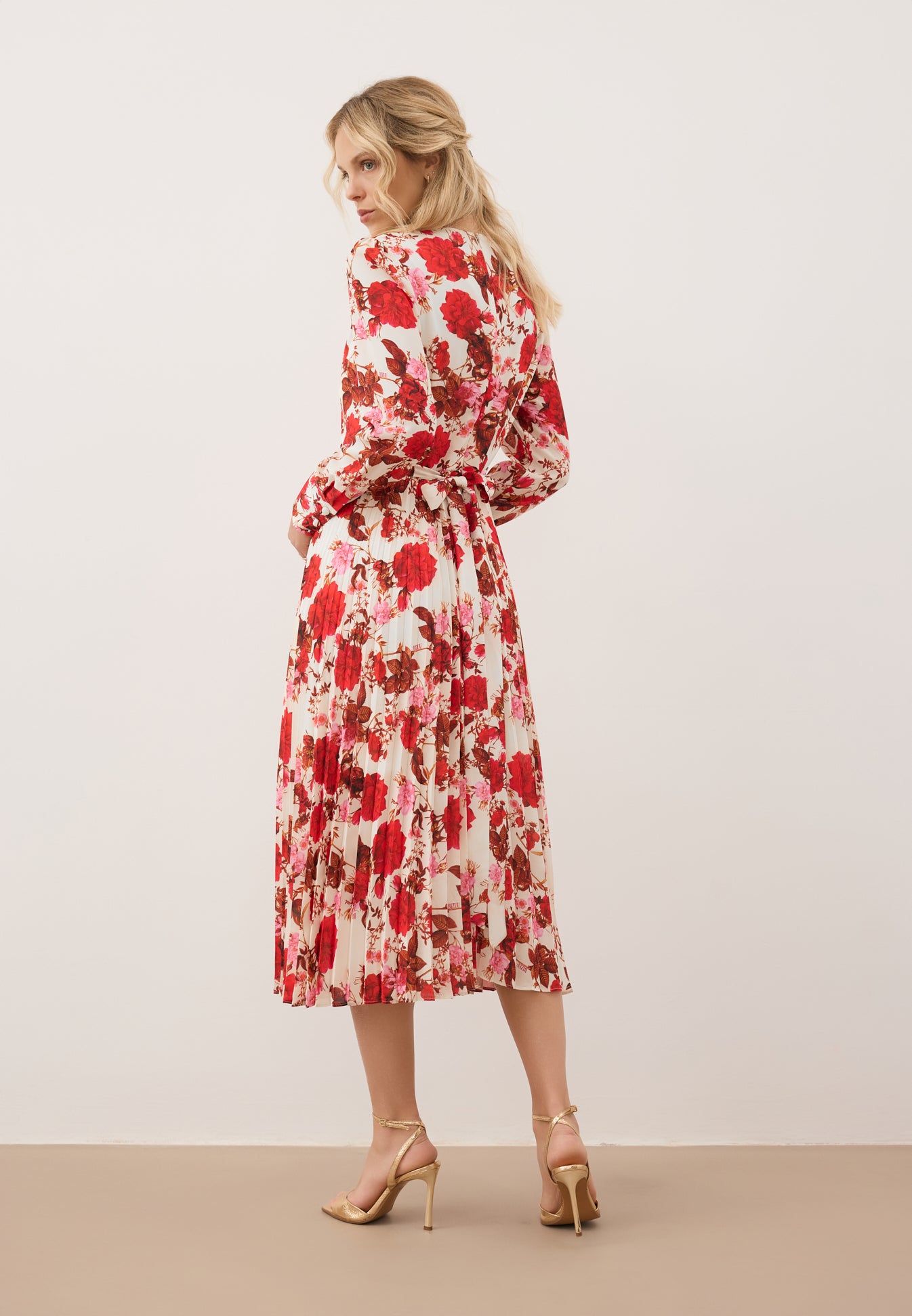 Modelka stojąca tyłem w midi sukience NYLA w kwiatowy print.