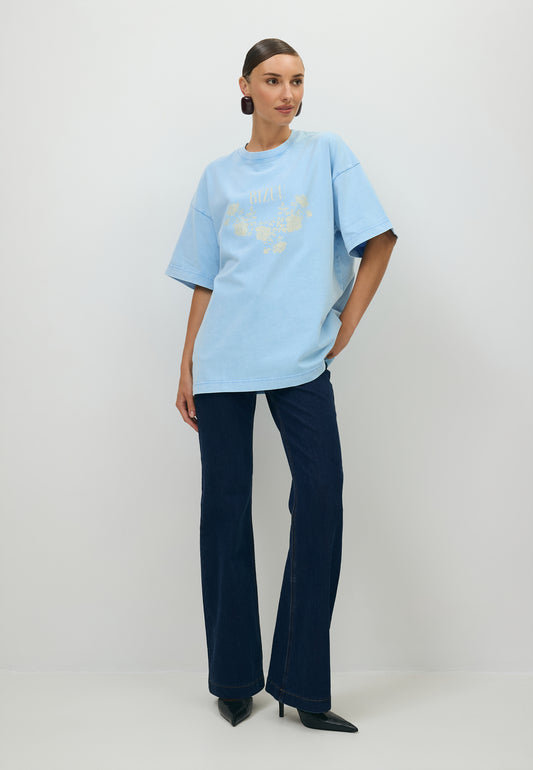 Modelka ubrana w błękitny T-shirt PAPLYS oraz granatowe jeansy.