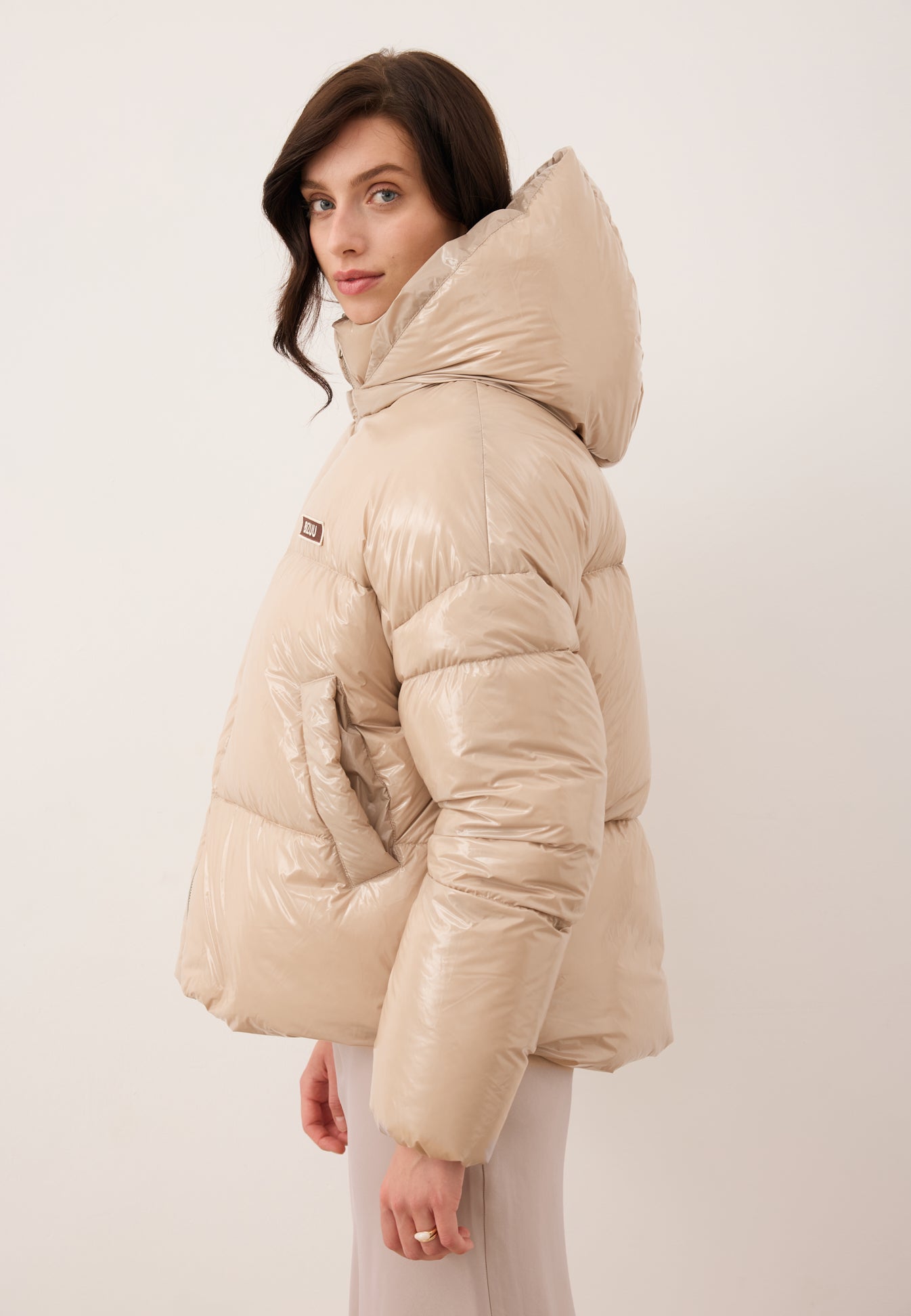 Modelka stojąca bokiem w puchowej kurtce SANYA w kolorze beżowym.