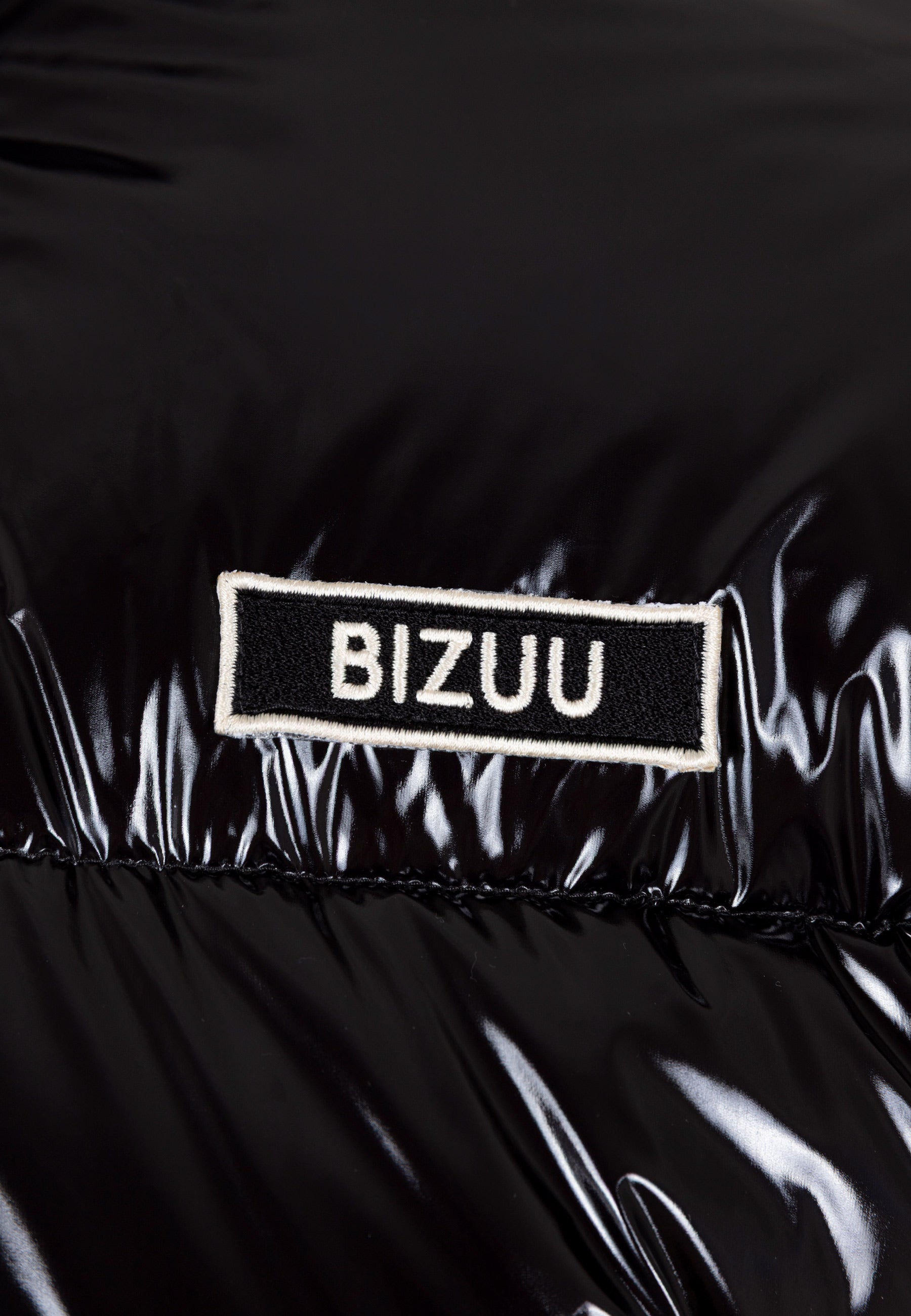 Zbliżenie na logo na przodzie kurtki puchowej SANYA.