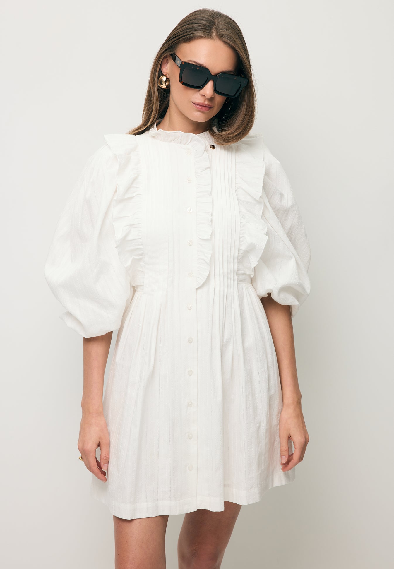 Modelka ubrana w białą sukienkę z ozdobnymi falbankami SULLY.