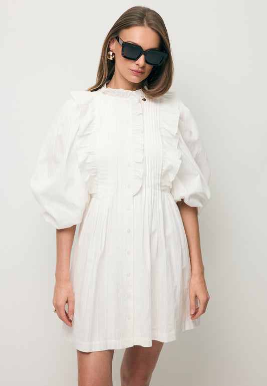 Modelka ubrana w białą sukienkę z ozdobnymi falbankami SULLY.