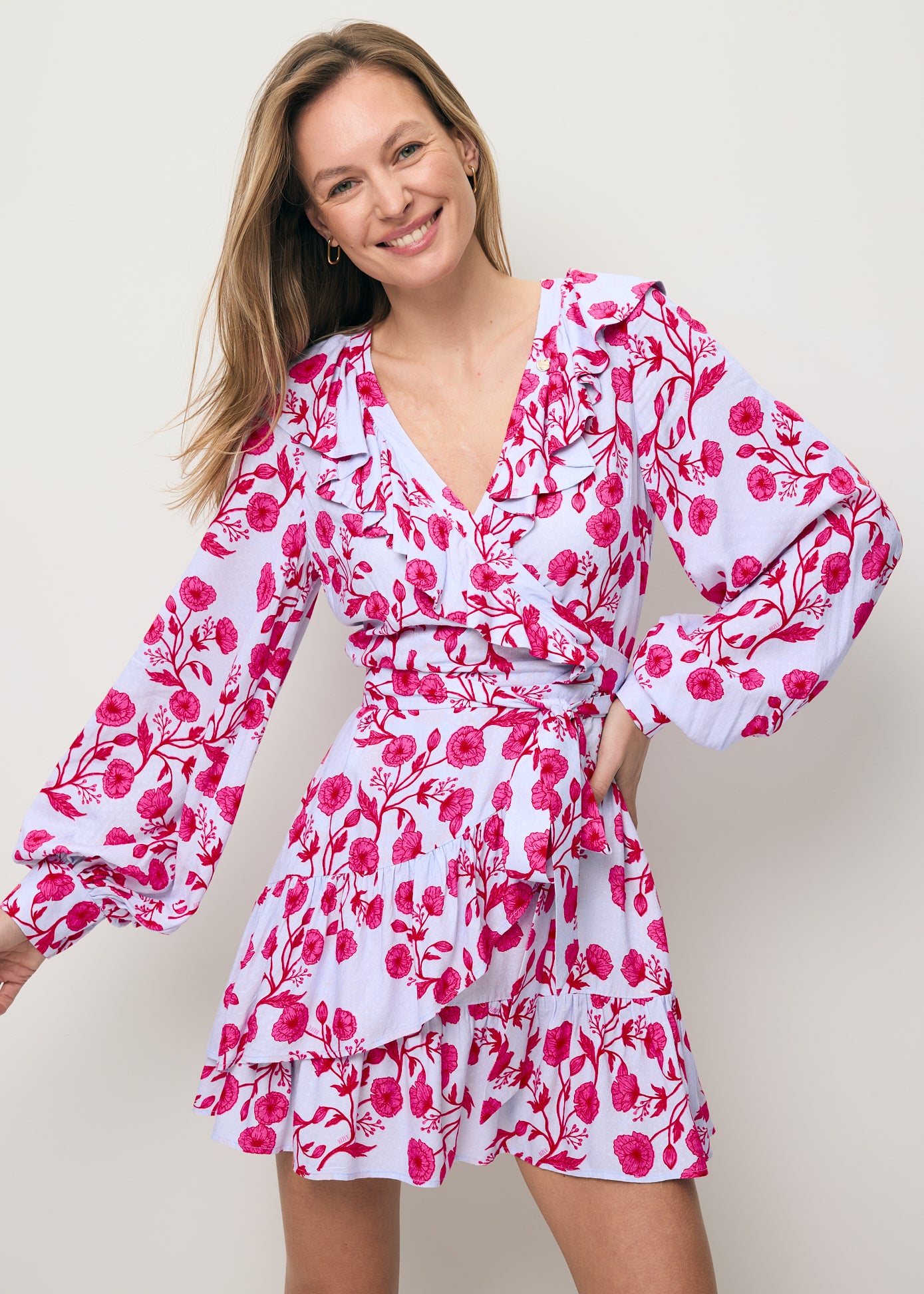 Zbliżenie na uśmiechniętą modelkę ubraną w mini sukienkę z ozdobnymi falbankami SYMA,