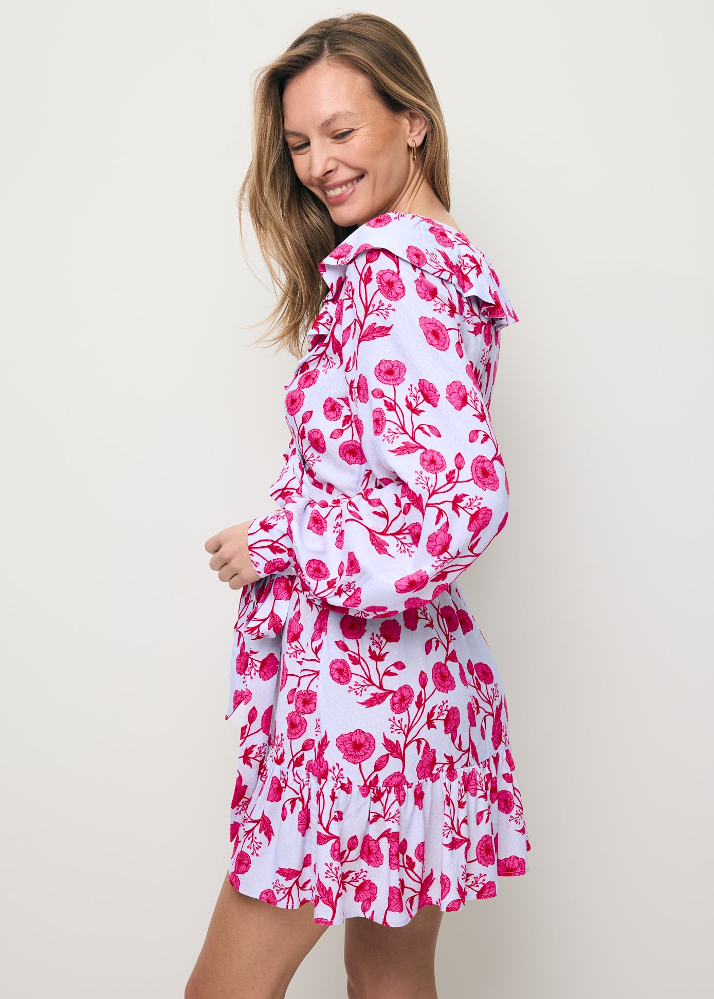 Modelka stojąca bokiem prezentująca bufiasty rękaw z ozdobną falbaną w sukience SYMA.