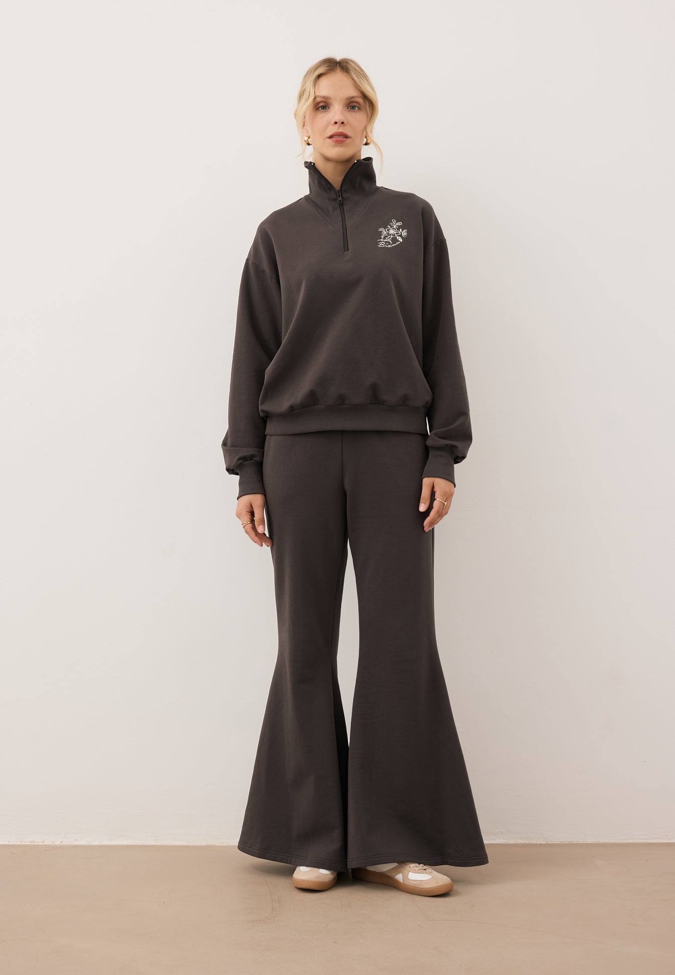 Modelka stojąca na wprost ubrana w bluzę half zip TANSY i spodnie z szerokimi nogawkami ZEIA,