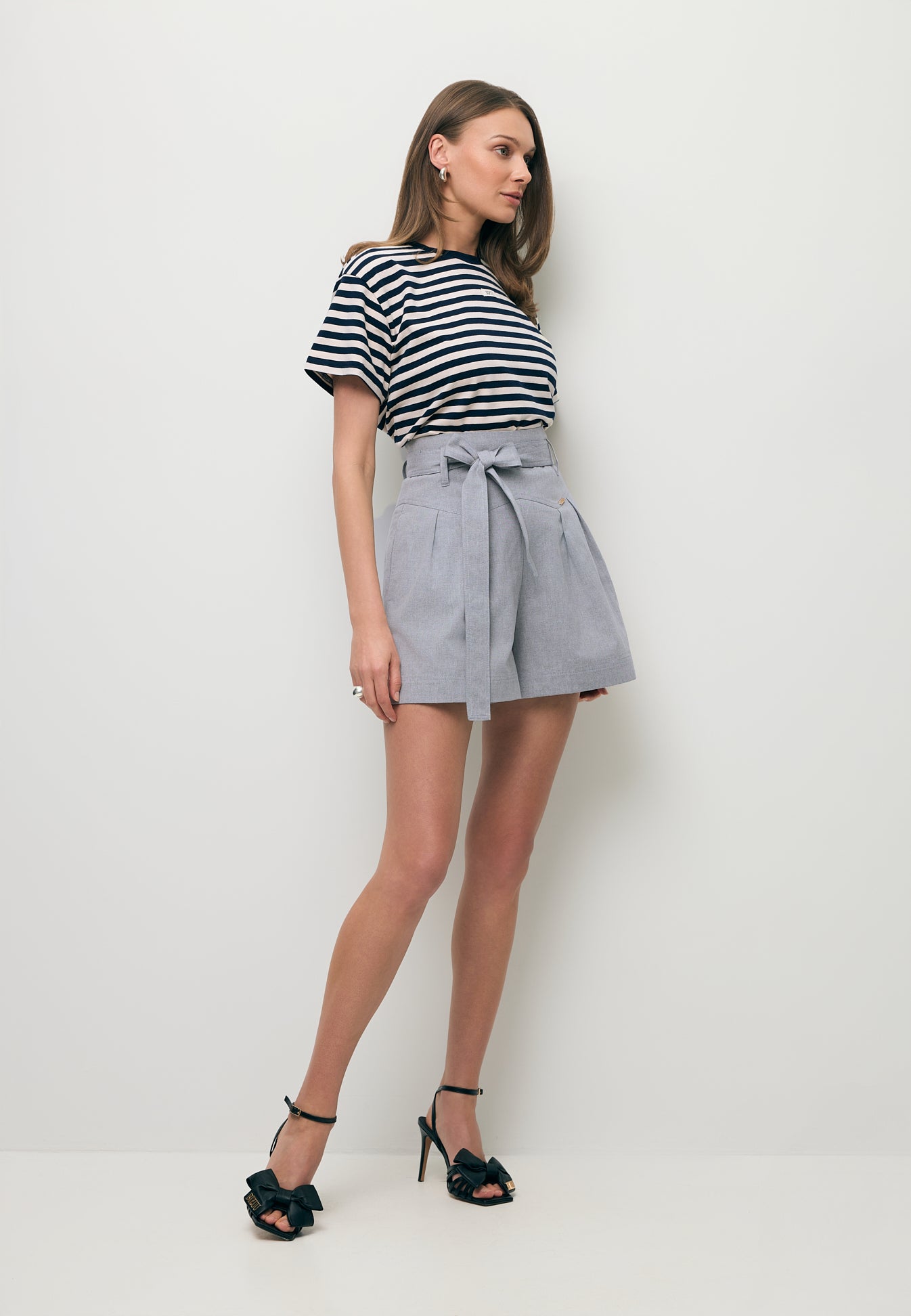 Modelka ubrana w T-shirt w paski TISHALLY oraz szare szorty KANDYS.