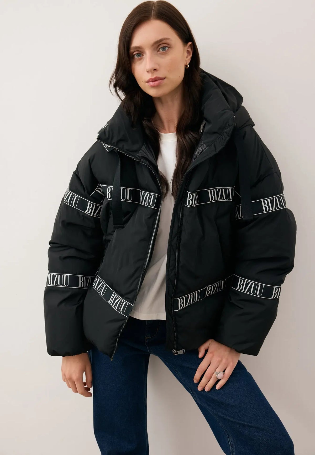 Modelka w rozpiętej czarnej, puchowej kurtce z logowaną taśmą TOKYO.
