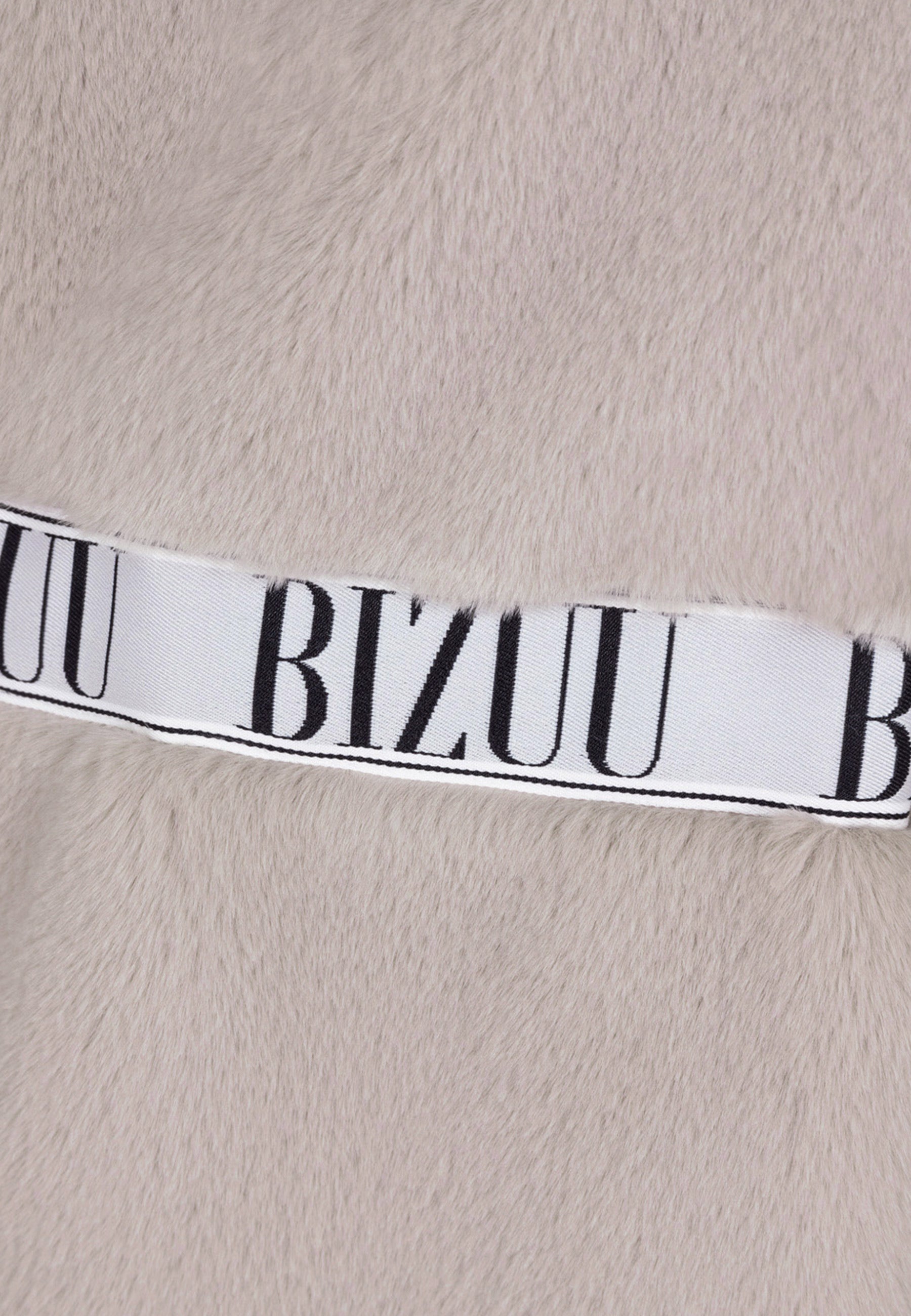 Zbliżenie na logo Bizuu na beżowym futrze FLORENCE.