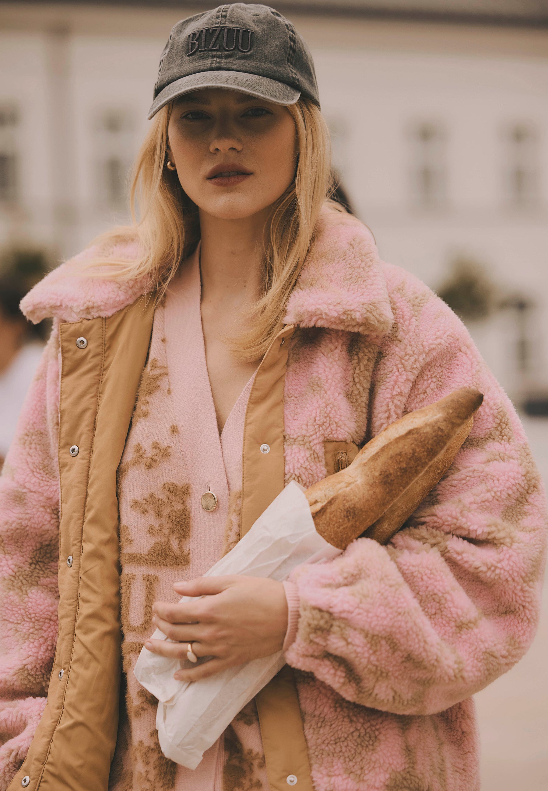 Modelka trzymająca bagietki ubrana w polarową kurtkę TEDDY oraz bawełnianą czapkę z daszkiem ZANE.